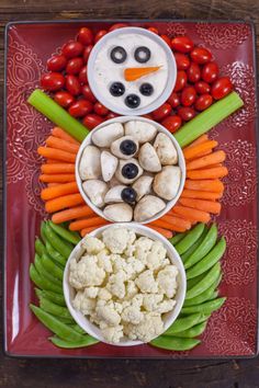 a plate with carrots, cauliflower, celery and other vegetables arranged in the shape of a snowman