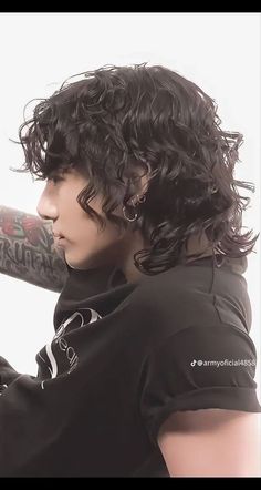 a young man with curly hair holding a baseball bat in his right hand and wearing a black t - shirt