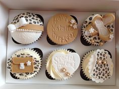 six decorated cupcakes in a box with leopard print and baby shoes on them