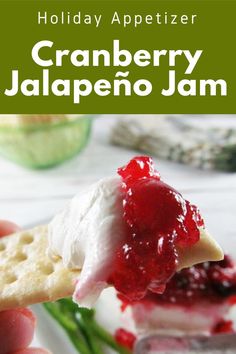 a hand holding a cracker with cranberry jalapeno jam on it