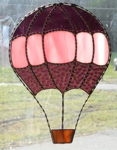 a stained glass hot air balloon sitting on top of a window sill in front of a grass field