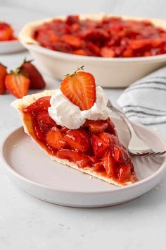 a slice of strawberry pie on a plate with whipped cream and strawberries in the background