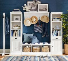 a room with blue walls and white shelves filled with hats, books, and other items