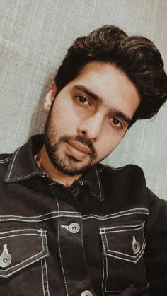 a man with black hair and beard wearing a black shirt is looking at the camera