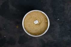 a white bowl filled with food sitting on top of a table next to a knife