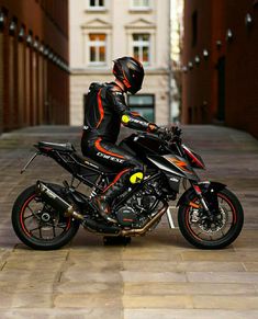 a man in black and orange riding on a motorcycle