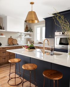 a kitchen with two stools in front of an island