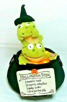 two stuffed animals sitting on top of a black pot with a sign that says halloween stew