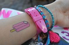 a woman's arm with a pink wristband and ice cream tattoo on it