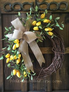 a wreath with yellow flowers hanging on a door