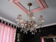 a chandelier hanging from the ceiling in a room with pink drapes and curtains