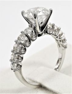 a close up view of a diamond ring on a white surface with the center stone surrounded by smaller stones