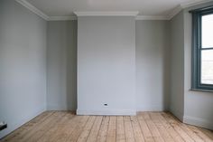 an empty room with white walls and wood floors