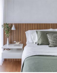 a bed with white sheets and green pillows