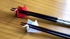 three chopsticks and two origami cranes on a table