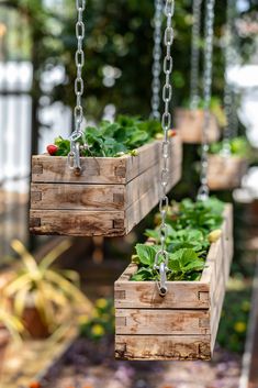 two wooden planters hanging from chains with plants in them