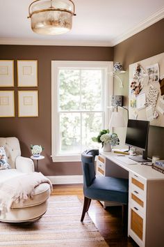 a room with a chair, desk and computer on the table in front of a window