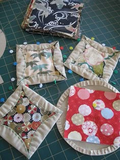 four square pieces of fabric sitting on top of a cutting board