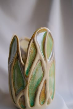 a close up of a ceramic object on a white surface with a cloth in the background