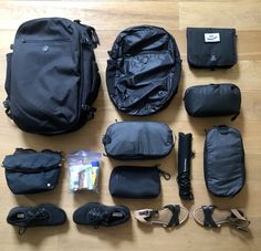 the contents of a black backpack laid out on a wooden floor