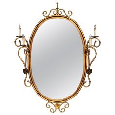 an ornately decorated gold mirror with two candles on the side and one candle in the middle