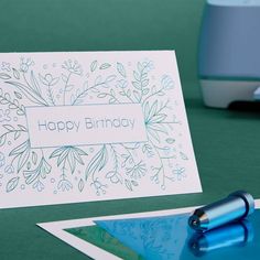 a happy birthday card sitting on top of a desk next to a pen and printer