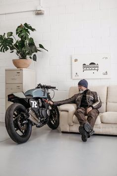 a man sitting on a couch next to a motorcycle