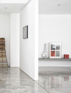 an empty room with white walls and flooring in the foreground is a stack of books