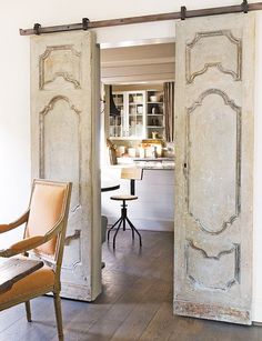 an open door leading to a kitchen and dining room with two chairs in front of it