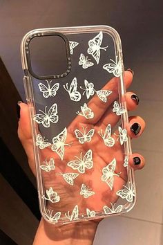 a woman's hand holding a clear case with white butterflies on it