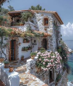 an old house with flowers growing out of it's windows next to the ocean