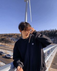 a young man standing next to a wind turbine