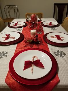 a table set for christmas with plates, candy canes and napkins on it