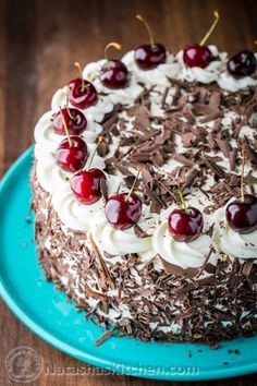 a chocolate cake with cherries and whipped cream toppings on a blue platter