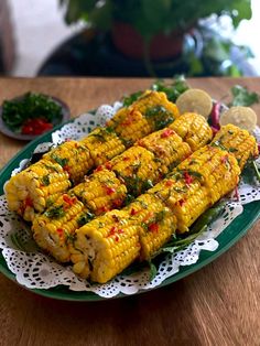 grilled corn on the cob with herbs and seasoning sitting on a green plate