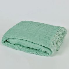 a green blanket folded on top of a white surface