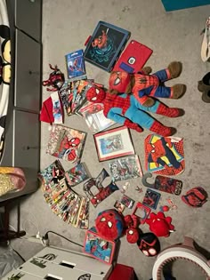 there are many spiderman toys on the floor next to some pictures and magnets