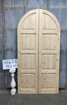 an arched wooden door sitting next to a sign