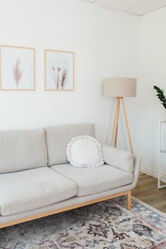 a living room with a white couch and two framed pictures on the wall above it