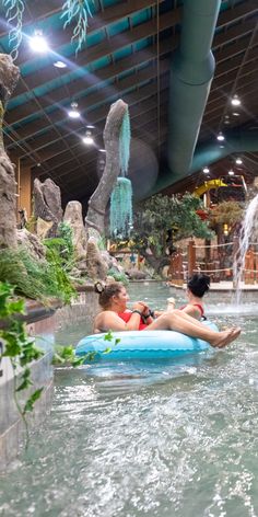 two women are in the water on an inner tube at a theme park, one is laying down and the other is standing up