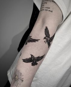 a person with a tattoo on their arm and two birds flying in the sky above them