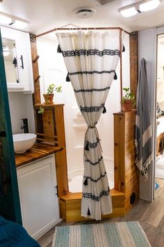 the inside of a camper with curtains hanging from it's ceiling and a rug on the floor