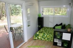 a small room with a bed, table and sliding glass doors leading to the outside