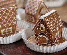 gingerbread houses are decorated with icing and sprinkles on a tray