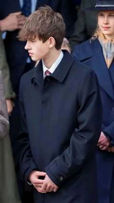 a boy in a black coat and hat standing next to other people