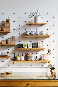 some shelves with various items on them and polka dots painted on the wall behind them