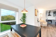 a kitchen with a black counter top next to a window and a wooden table in front of it