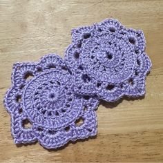 two crocheted coasters sitting on top of a wooden table