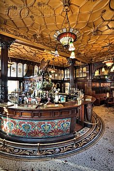 an old fashioned bar with many bottles on the counter and chandelier hanging from the ceiling