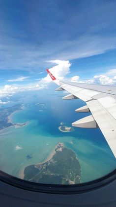 an airplane wing flying over the ocean and land